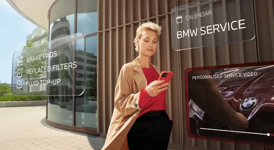 image Frau mit BMW im Hintergrund und Handy in der Hand