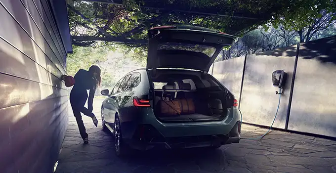 Frau steht bei BMW i5 Touring zum Ausladen.